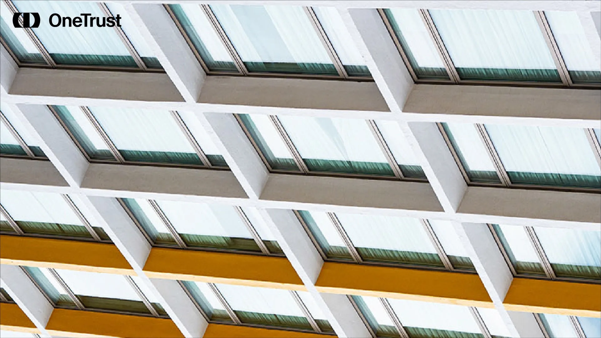 A repeating architectural pattern of angled glass windows and white structural beams.